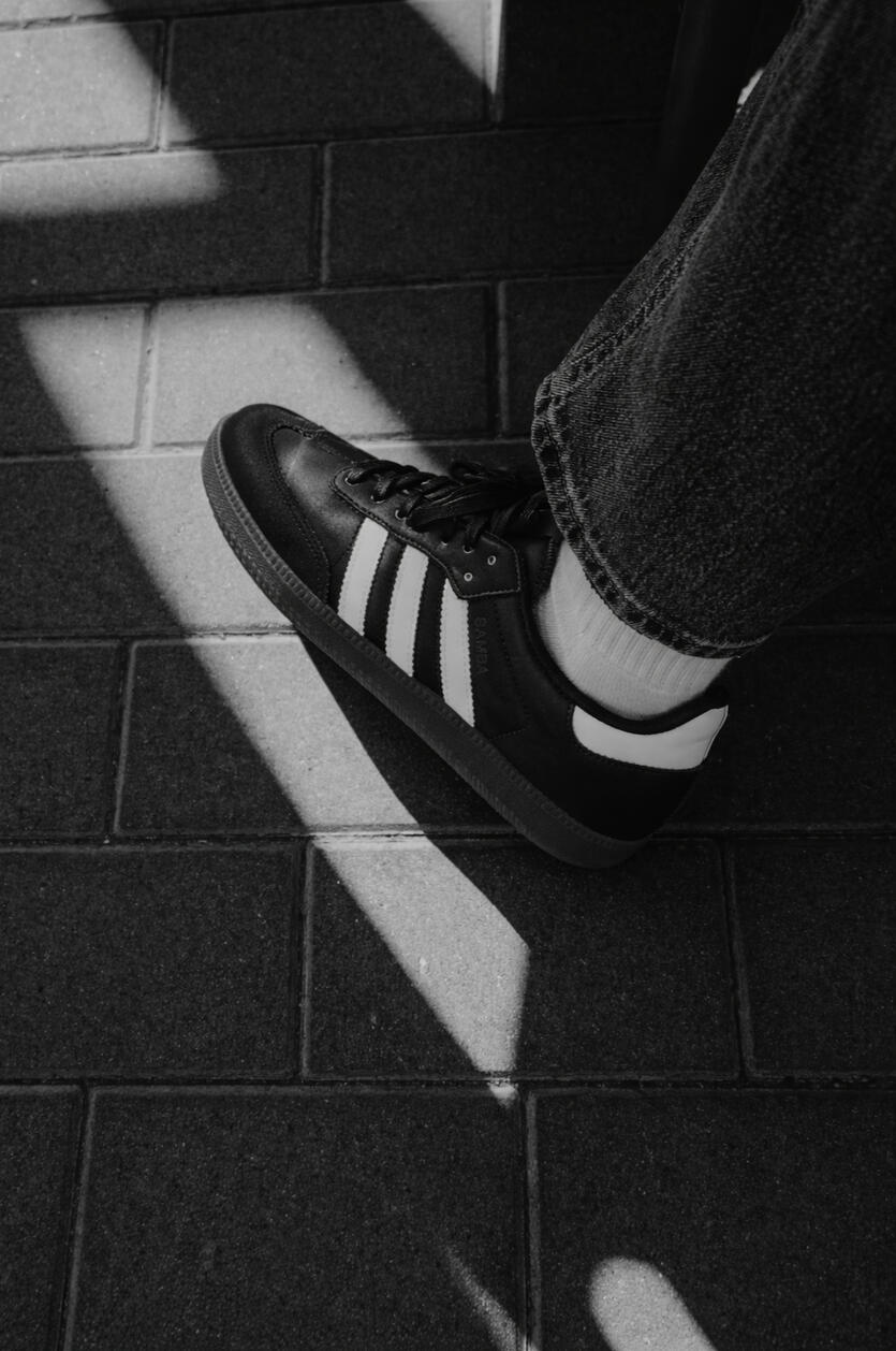 person wearing black adidas samba sneakers person wearing black adidas samba sneakers